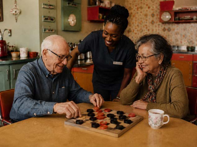 A volunteer joins two members for a game of checkers